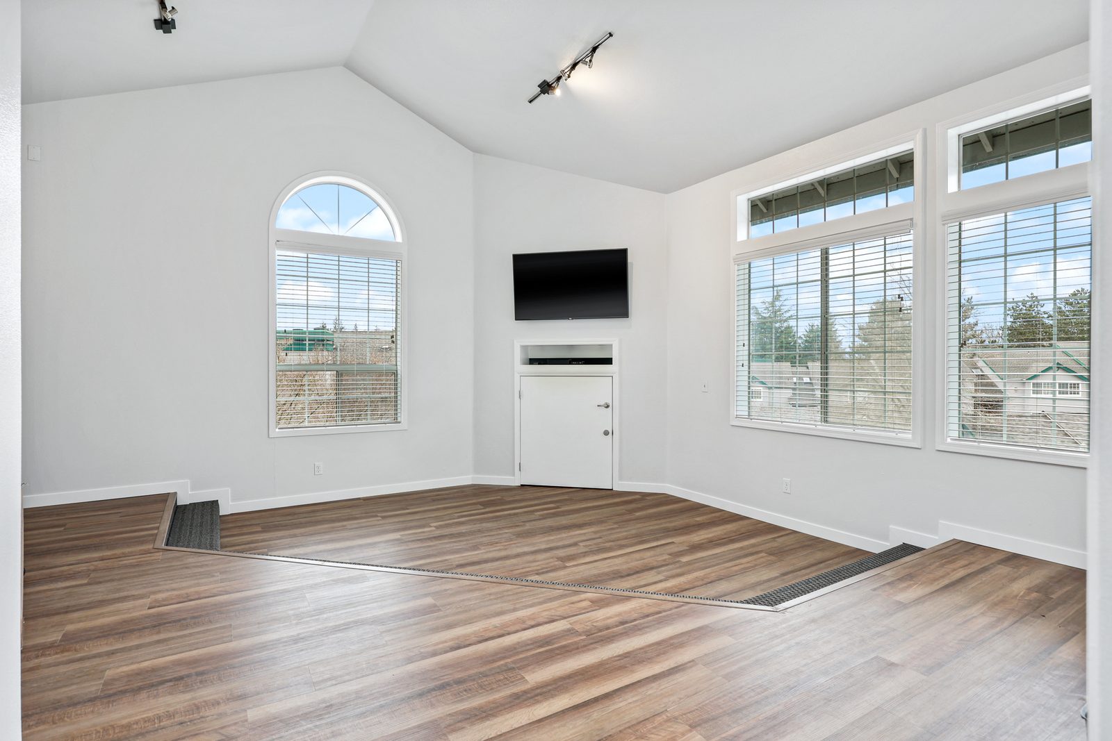 Living room with vaulted ceilings and an arched window